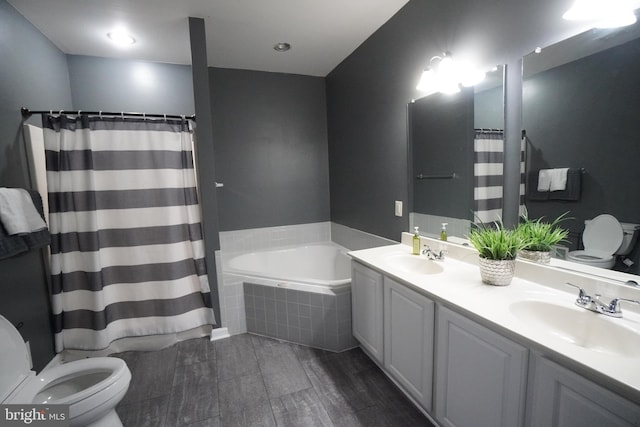 bathroom featuring vanity, tiled bath, and toilet