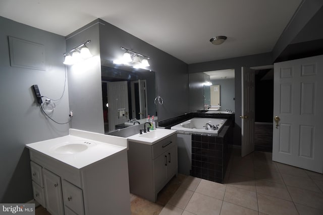 bathroom with tile patterned flooring, vanity, and a relaxing tiled tub