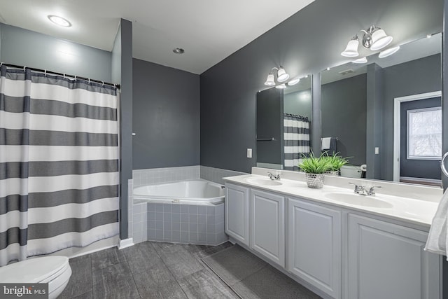 bathroom featuring tiled tub and vanity