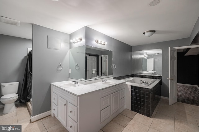 bathroom with tile patterned flooring, vanity, toilet, and tiled tub