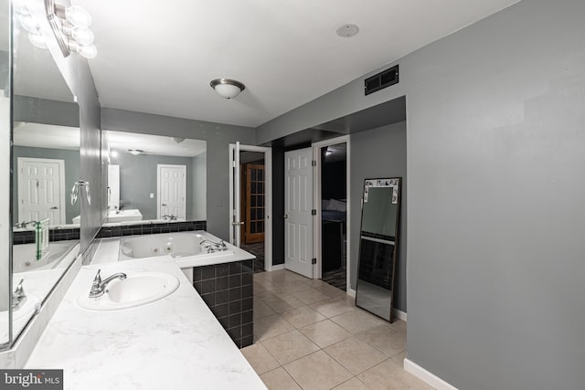 bathroom with tiled tub, vanity, and tile patterned floors