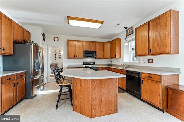 kitchen with black appliances, a breakfast bar, a center island, and sink