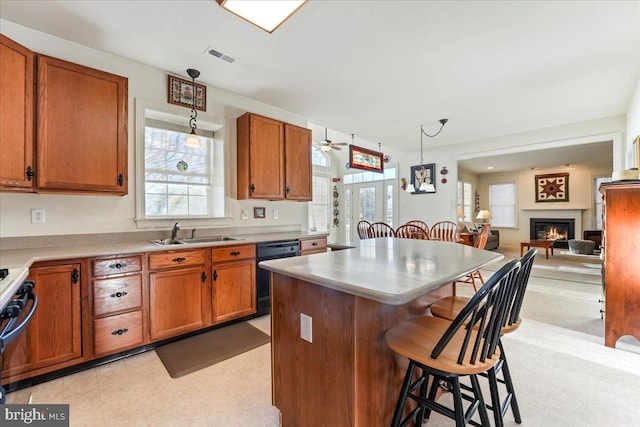 kitchen with sink, black dishwasher, decorative light fixtures, a kitchen island, and a kitchen bar