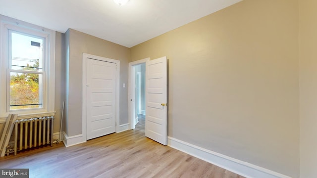 unfurnished room with light hardwood / wood-style floors and radiator