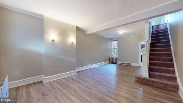 interior space with radiator heating unit, ornamental molding, and light wood-type flooring