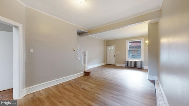 unfurnished living room with light hardwood / wood-style floors, radiator, and crown molding