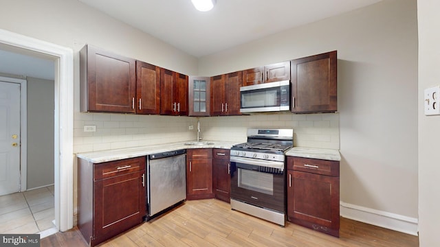 kitchen featuring light stone counters, light hardwood / wood-style flooring, sink, and appliances with stainless steel finishes