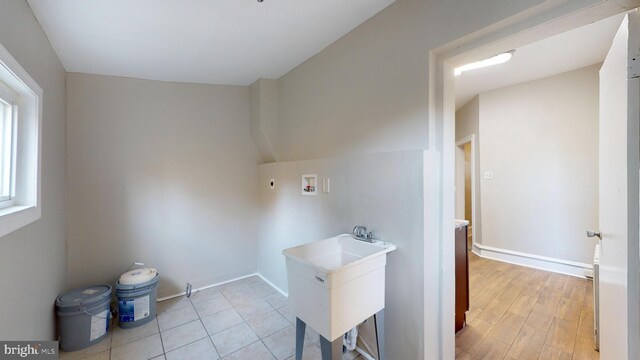 washroom with light hardwood / wood-style flooring, washer hookup, and sink