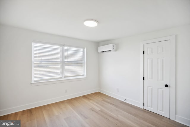 spare room with light wood-type flooring and an AC wall unit