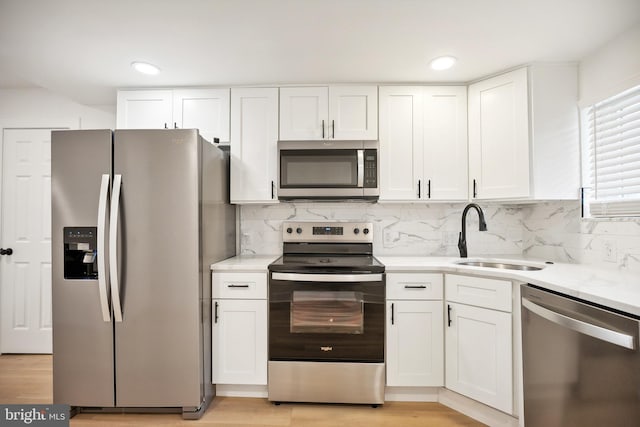 kitchen featuring white cabinets, sink, appliances with stainless steel finishes, tasteful backsplash, and light hardwood / wood-style floors