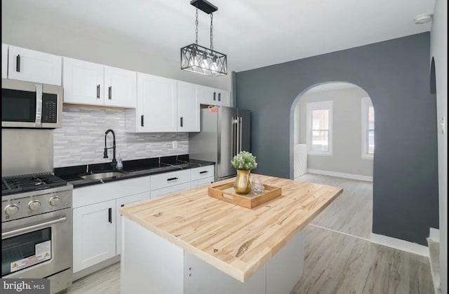 kitchen with a center island, white cabinets, decorative light fixtures, light hardwood / wood-style flooring, and premium appliances