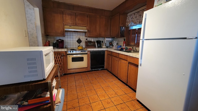 kitchen featuring white appliances, tile countertops, tasteful backsplash, and sink