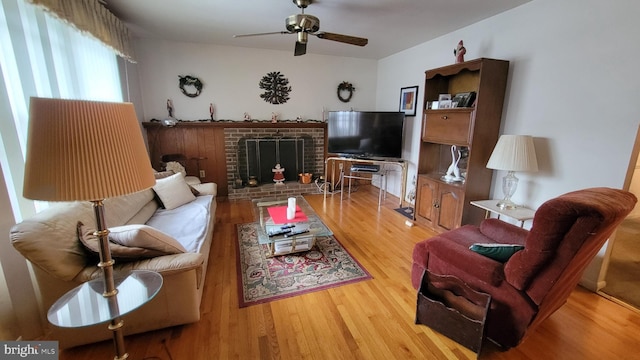 living room featuring ceiling fan, a fireplace, and light hardwood / wood-style flooring