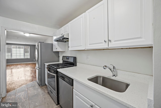 kitchen with white cabinets, stainless steel appliances, light stone counters, and sink