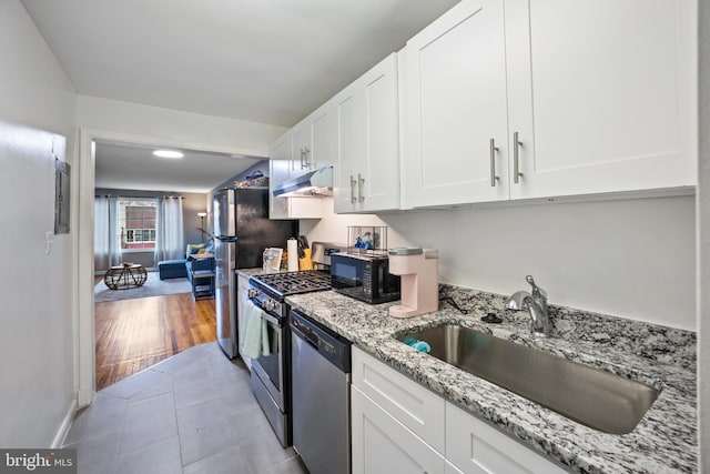 kitchen featuring white cabinets, sink, light hardwood / wood-style flooring, light stone countertops, and appliances with stainless steel finishes