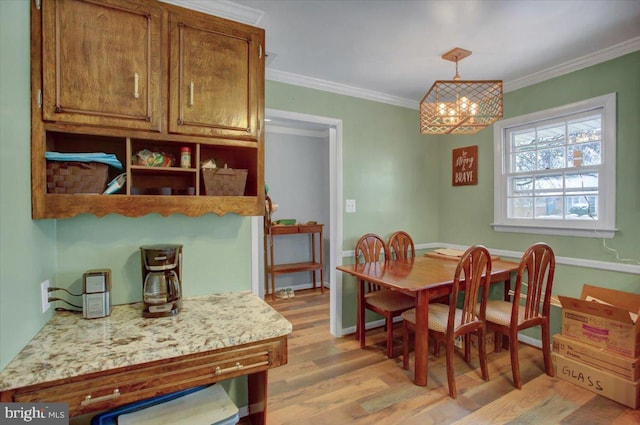 dining space with crown molding, light hardwood / wood-style floors, and a notable chandelier