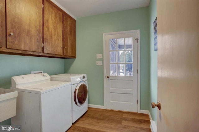 laundry area with washer and dryer, cabinets, sink, and light hardwood / wood-style flooring