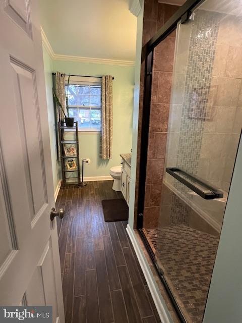 bathroom with crown molding, an enclosed shower, toilet, vanity, and hardwood / wood-style flooring