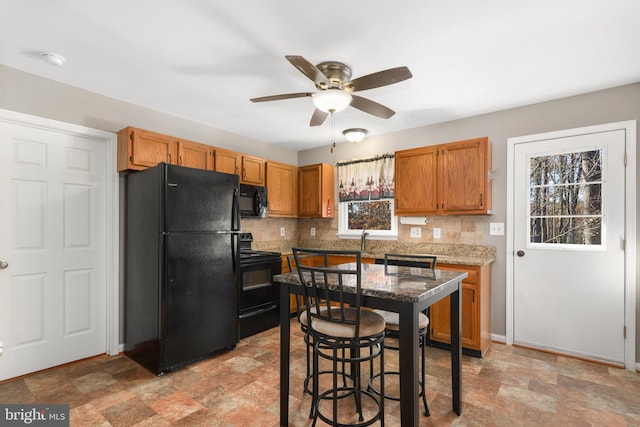 kitchen with decorative backsplash, light stone counters, ceiling fan, sink, and black appliances