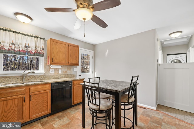 kitchen with light stone counters, sink, black dishwasher, and a wealth of natural light