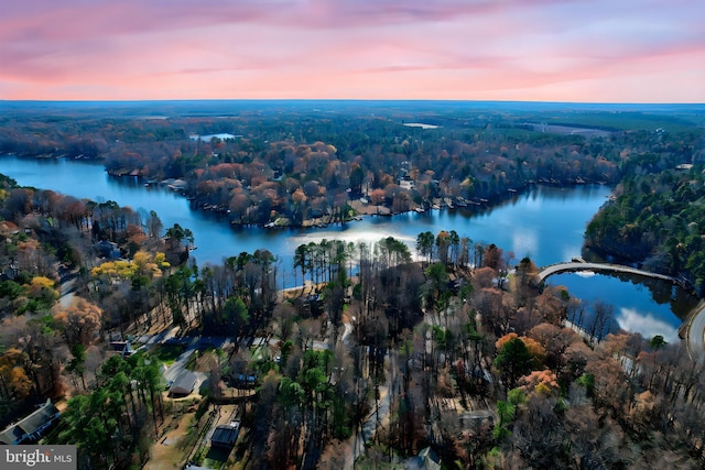 aerial view at dusk featuring a water view