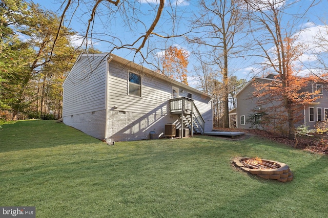 rear view of house with a fire pit, a yard, and central AC