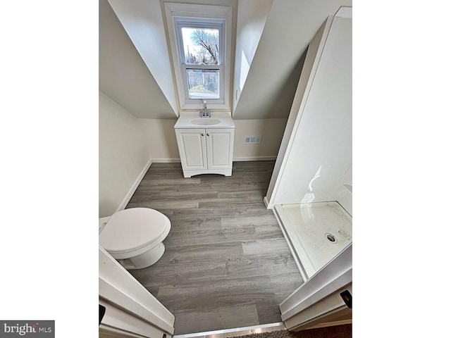 bathroom with a shower, vanity, hardwood / wood-style flooring, and toilet