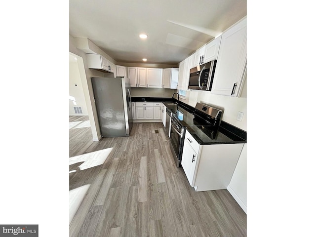 kitchen with white cabinets, stainless steel appliances, light hardwood / wood-style floors, and sink