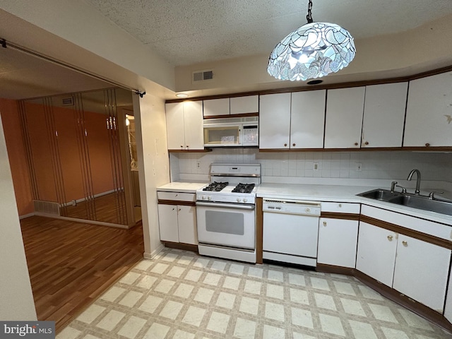 kitchen featuring white appliances, backsplash, light hardwood / wood-style flooring, decorative light fixtures, and white cabinetry