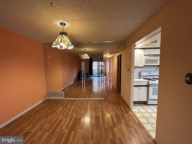 unfurnished dining area with a textured ceiling and light wood-type flooring