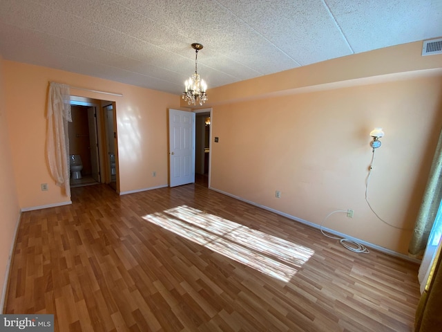 unfurnished room featuring hardwood / wood-style floors and a chandelier