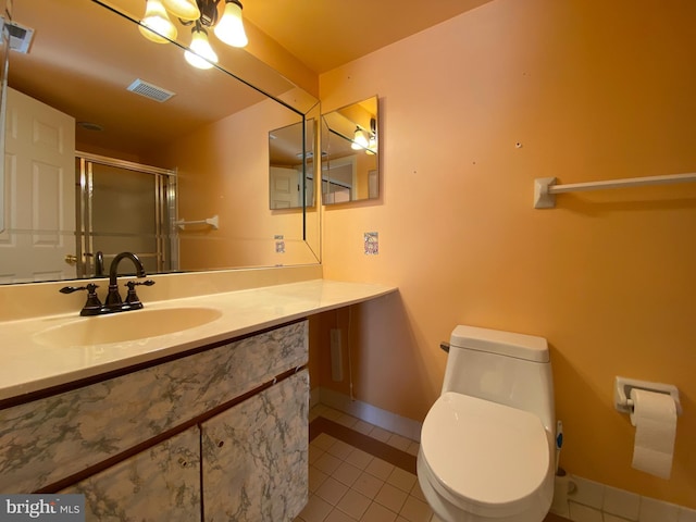 bathroom featuring toilet, vanity, tile patterned floors, and a shower with shower door