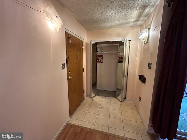 hallway with light tile patterned floors and a textured ceiling