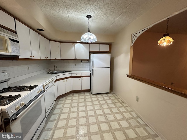 kitchen with decorative light fixtures, white cabinetry, white appliances, and sink