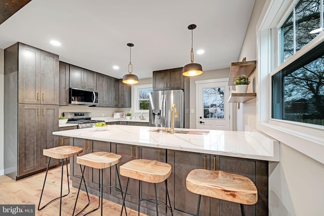 kitchen featuring sink, a breakfast bar area, light hardwood / wood-style flooring, kitchen peninsula, and stainless steel appliances