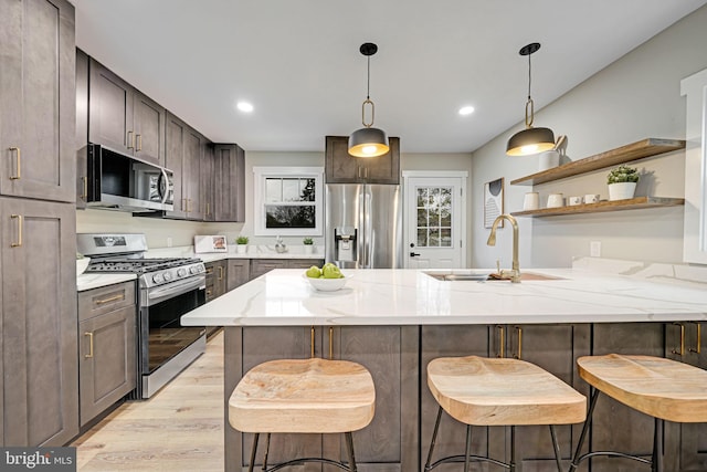 kitchen with a breakfast bar, sink, stainless steel appliances, and light hardwood / wood-style floors