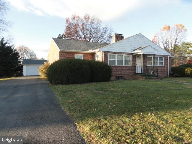 view of front facade with an outdoor structure, a front yard, and a garage