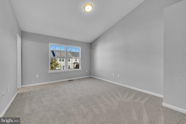 carpeted empty room with vaulted ceiling