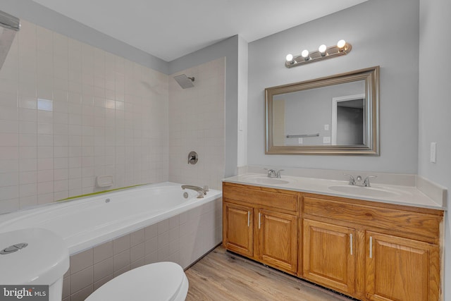 full bathroom with hardwood / wood-style floors, vanity, toilet, and tiled shower / bath