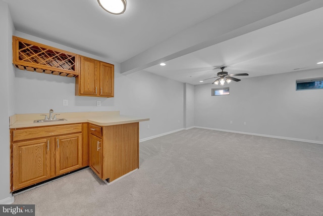 kitchen featuring sink, ceiling fan, beam ceiling, light colored carpet, and kitchen peninsula