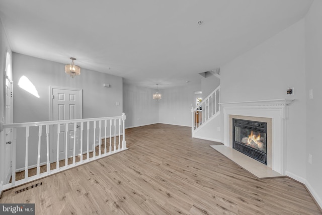 unfurnished living room featuring light hardwood / wood-style floors and a chandelier