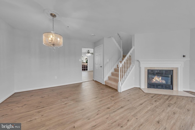 unfurnished living room with a fireplace, light hardwood / wood-style floors, and a notable chandelier