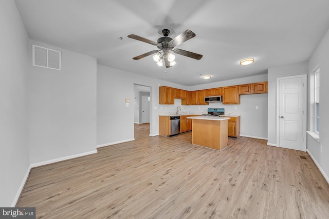 kitchen featuring ceiling fan, sink, stainless steel appliances, light hardwood / wood-style floors, and a kitchen island