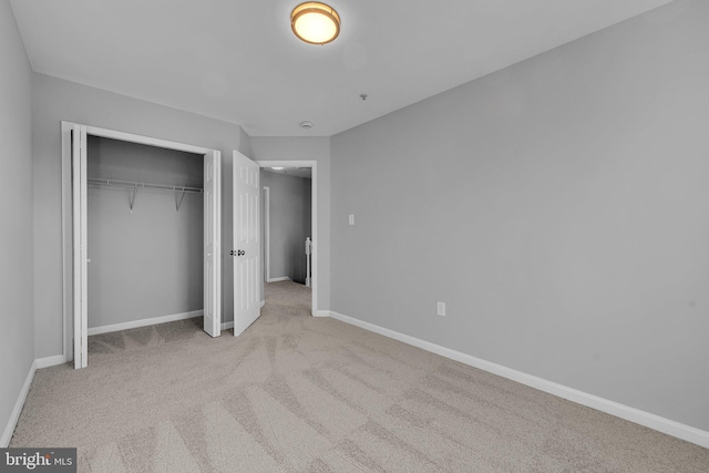 unfurnished bedroom featuring light carpet and a closet