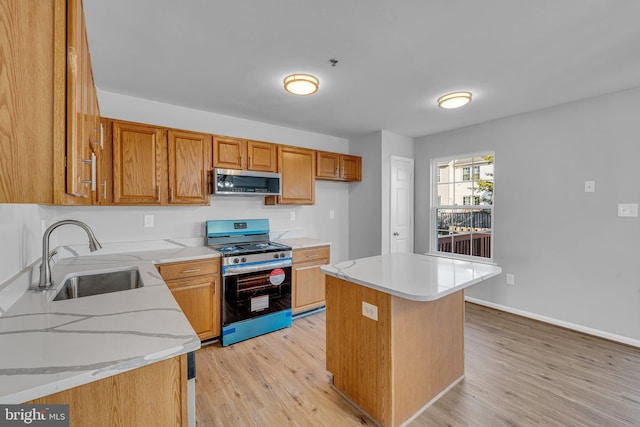 kitchen featuring a center island, sink, light stone counters, light hardwood / wood-style flooring, and gas range oven