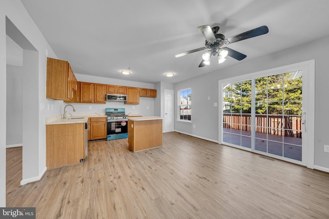 kitchen featuring a center island, sink, ceiling fan, light wood-type flooring, and appliances with stainless steel finishes