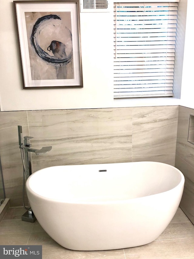 bathroom with tile patterned flooring, a bath, and tile walls