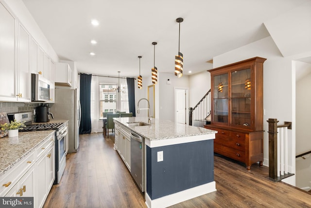 kitchen with stainless steel appliances, a sink, backsplash, and dark wood-style floors