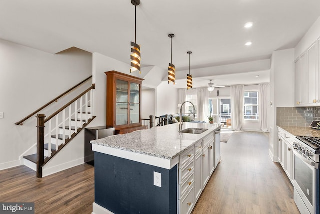 kitchen featuring stainless steel appliances, dark wood-style flooring, a sink, and decorative backsplash