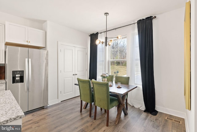 dining area featuring a chandelier, light wood-type flooring, visible vents, and baseboards